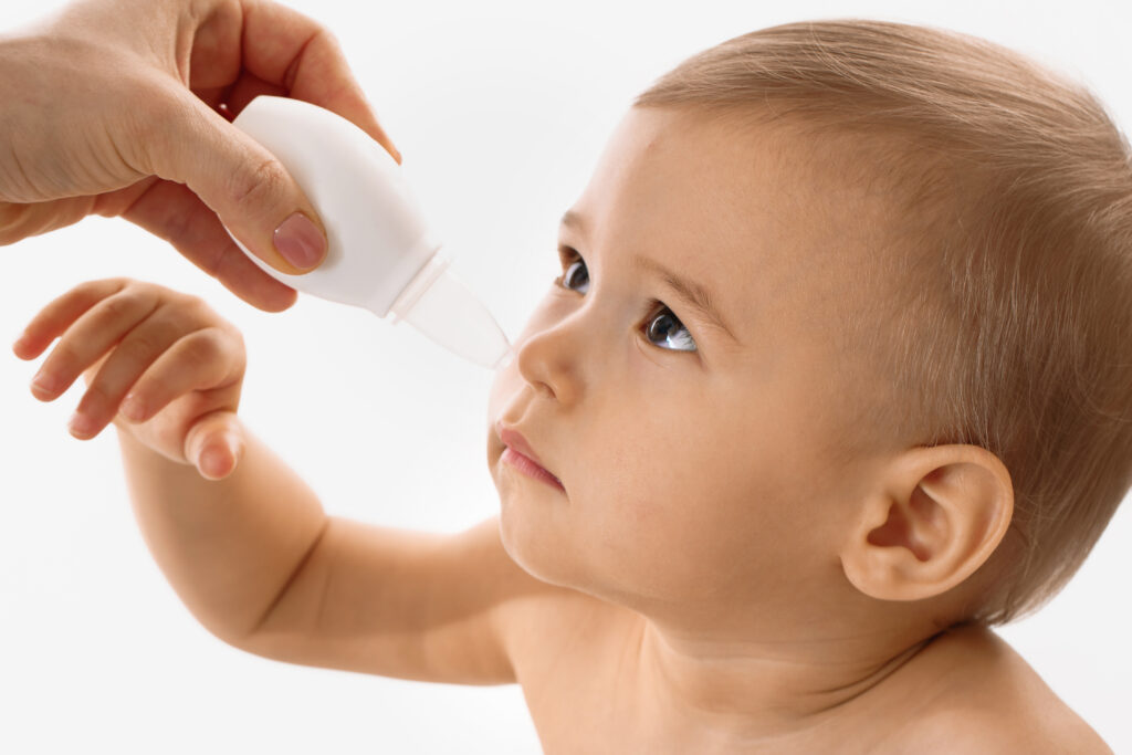 mother using nasal aspirator on her child nose